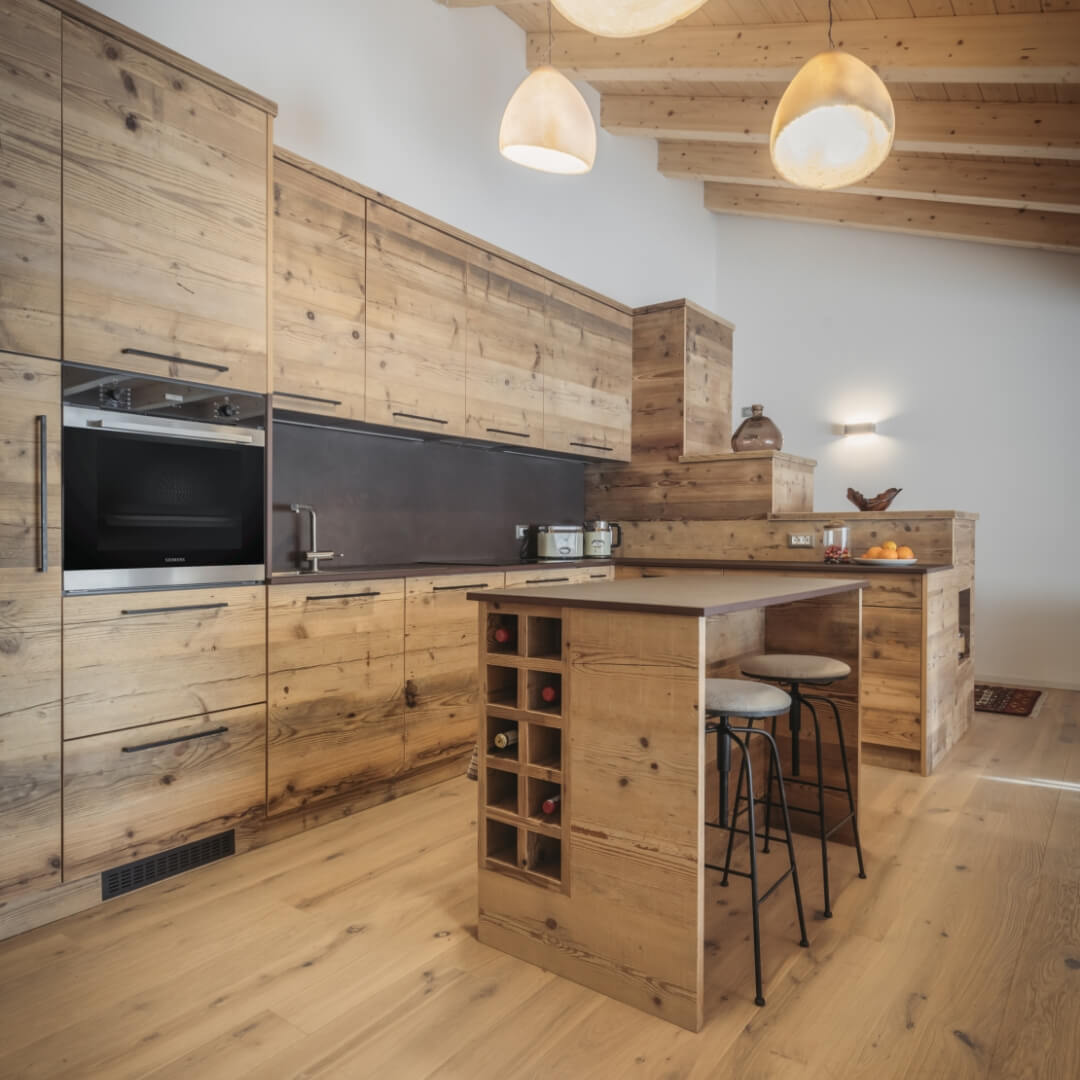 Cucina su misura realizzata in legno con bancone centrale porta bottiglie e con sgabelli