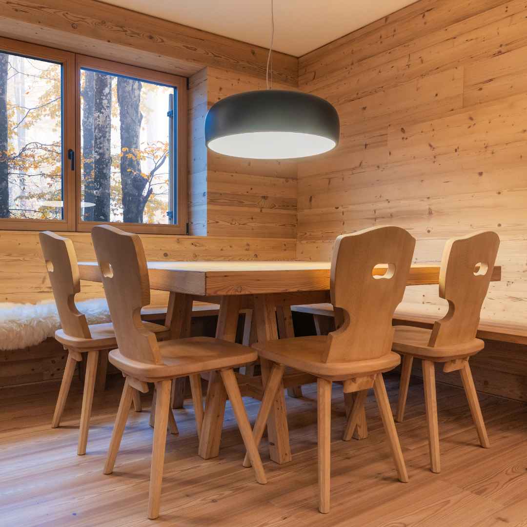 Tavolo sedie e panche compongono la zona pranzo e cena di una casa di montagna