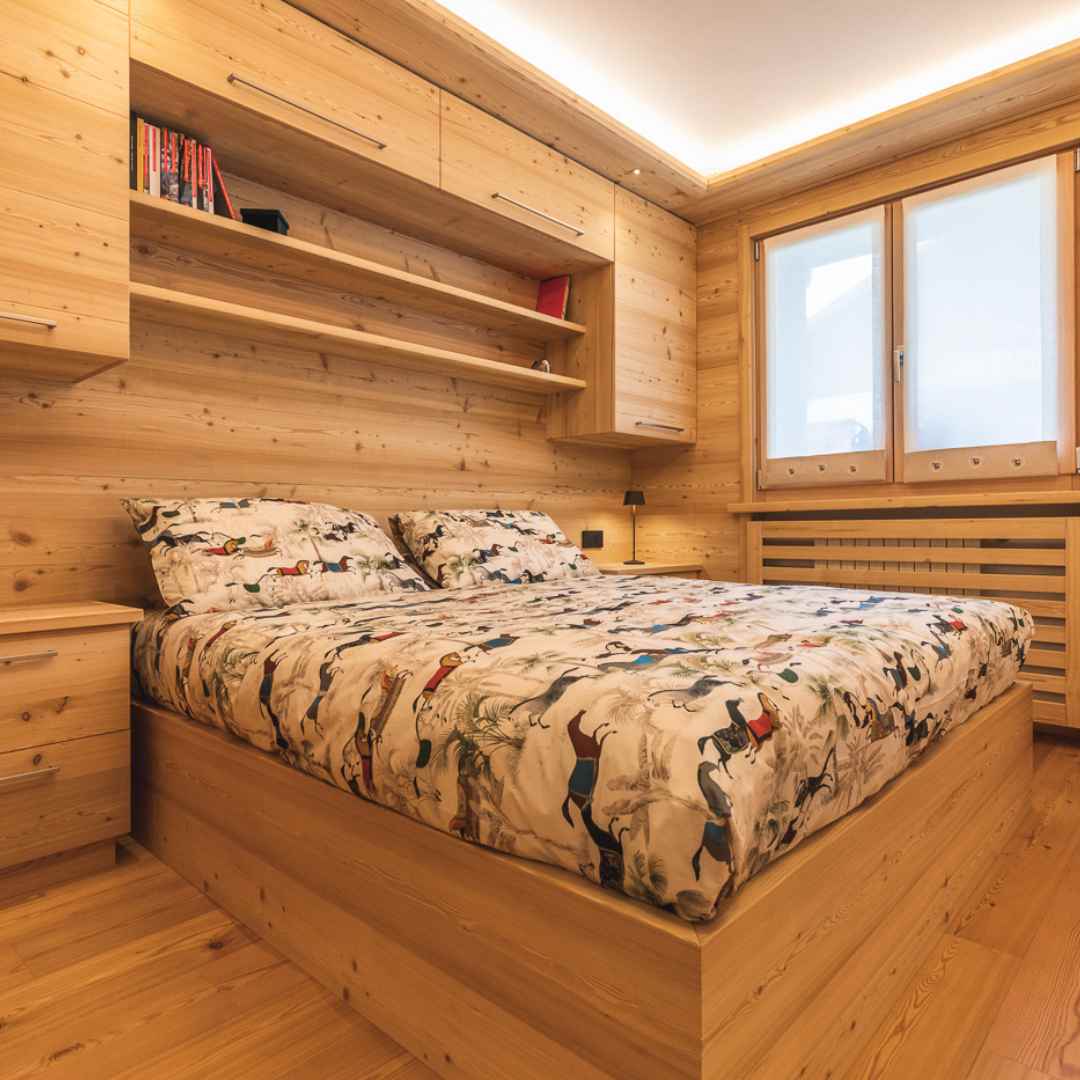 Camera rivestita in legno di larice con mobilio dello stesso legno